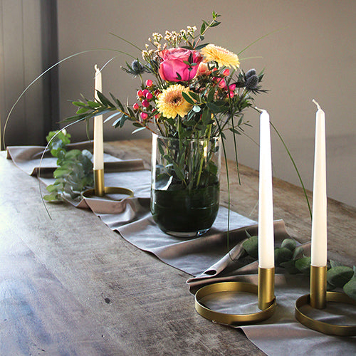 Moderne Tischdekoration mit goldenen Kerzenständer, rustikalem Tisch und schönem Blumenstrauß. In den Farben Gelb und Pink