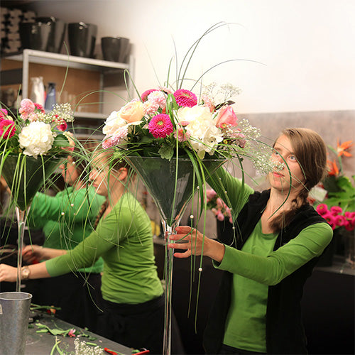 Floristinnen von Konzelmann-Höfer bei der Arbeit. Sie stecken Tischgestecke in den Farben Weiß und Pink. Hochwertige und anspruchsvolle Floristik.